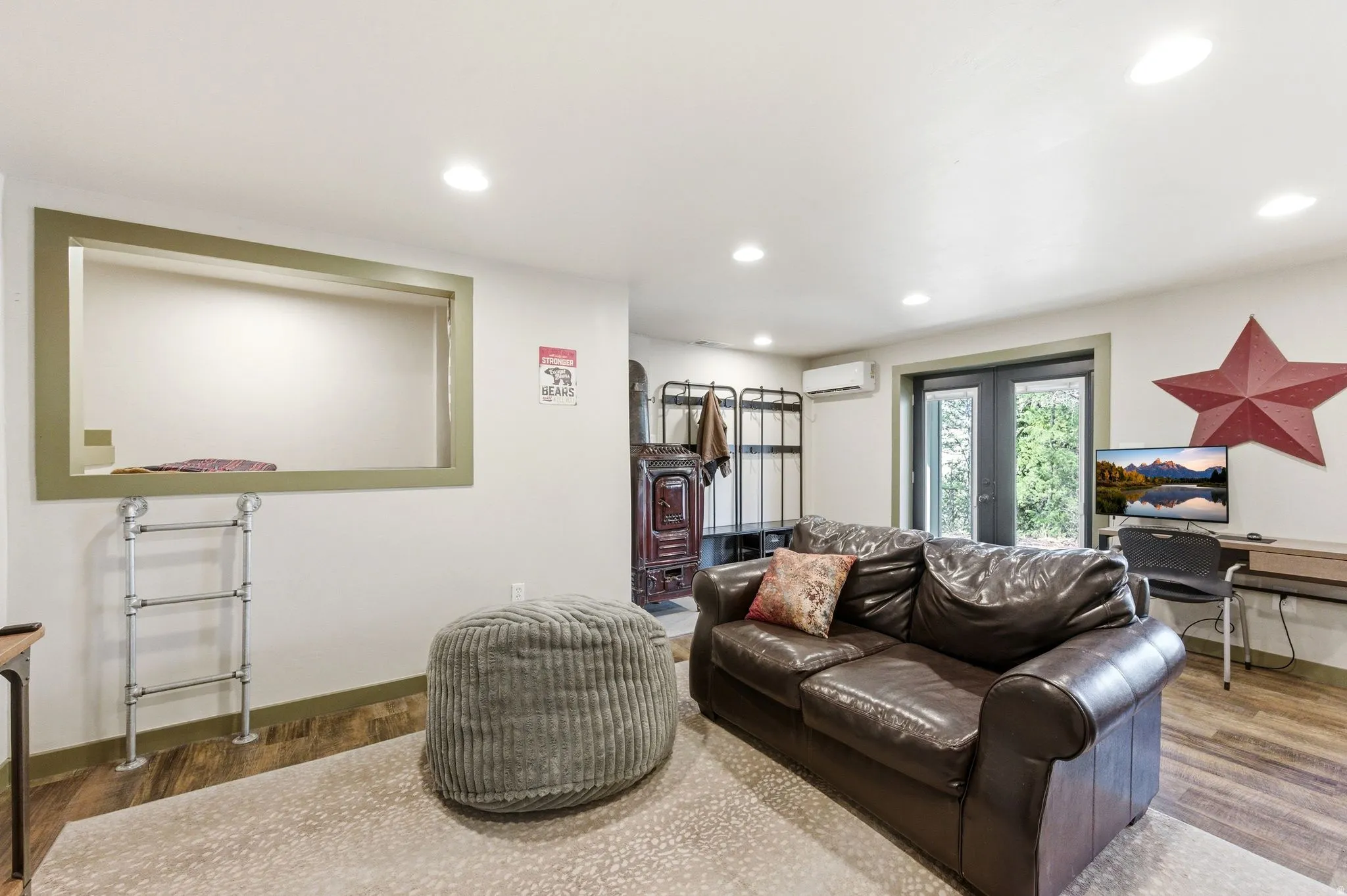 Downstairs living room with french doors, LVP floors, sleeping nook, wood or coal burning stove and recessed lighting