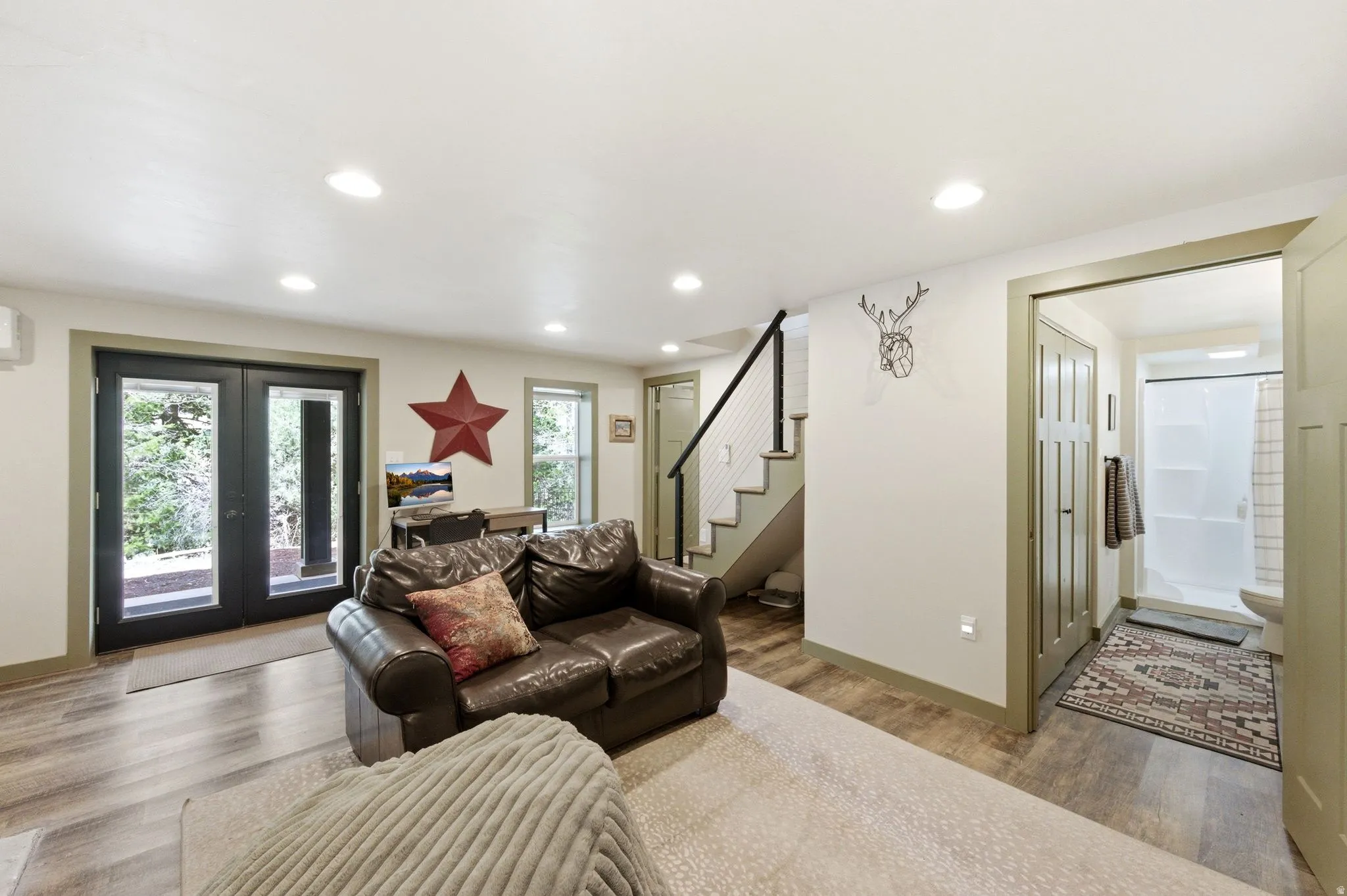 Downstairs living room with french doors, LVP floors, sleeping nook, wood or coal burning stove and recessed lighting