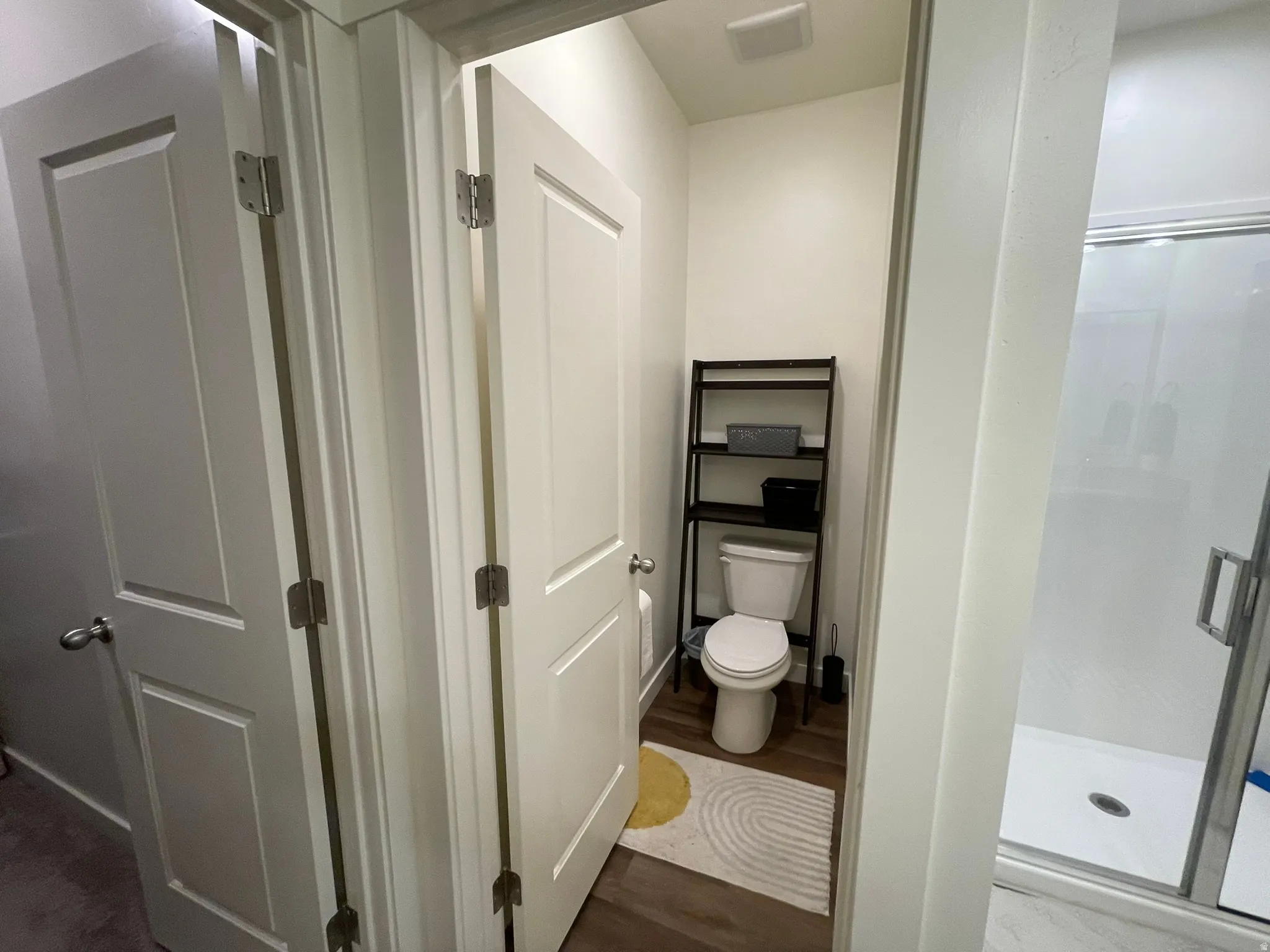 Bathroom with a stall shower and dark wood-style flooring