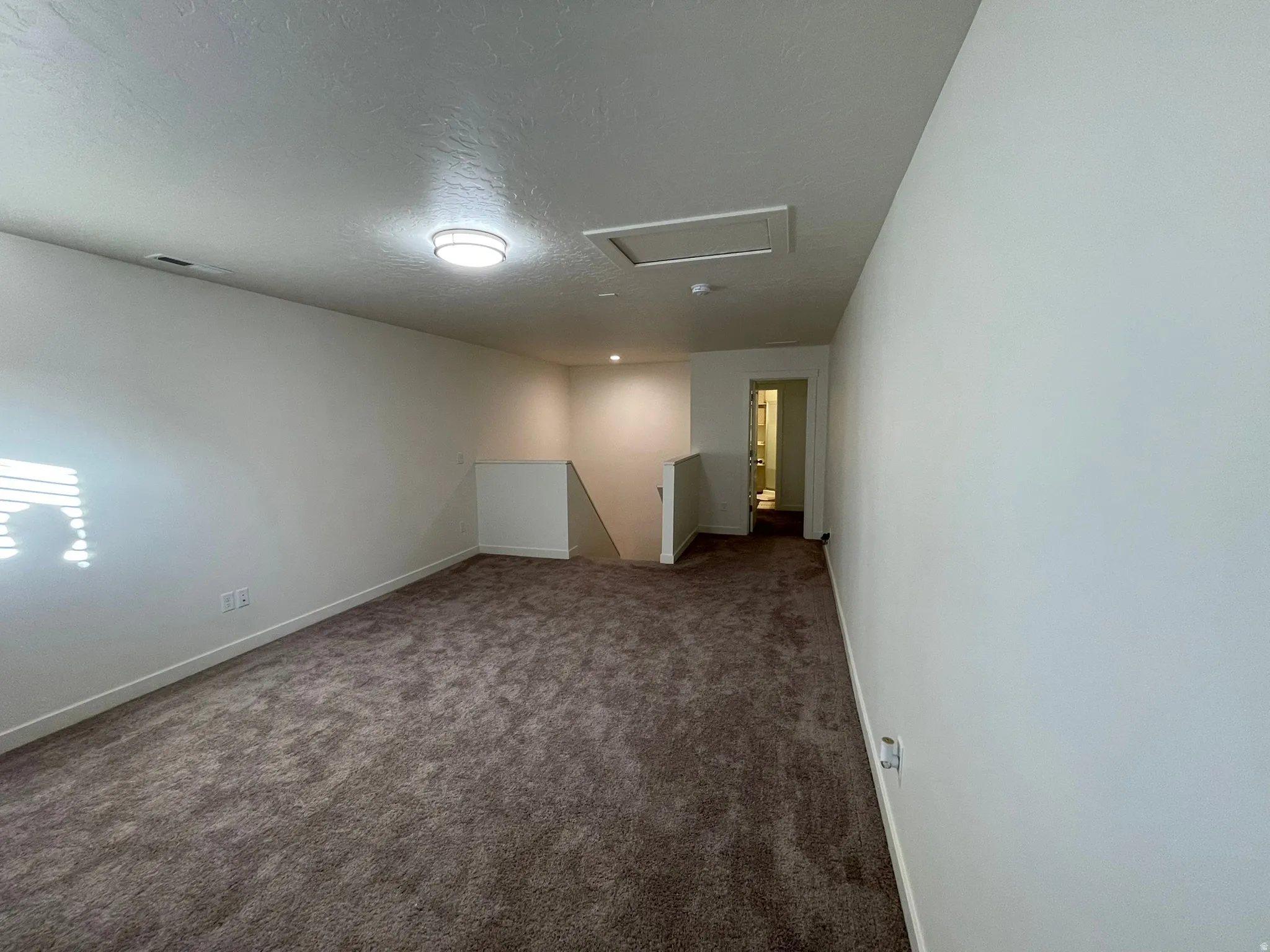 Spare room featuring dark colored carpet and a textured ceiling