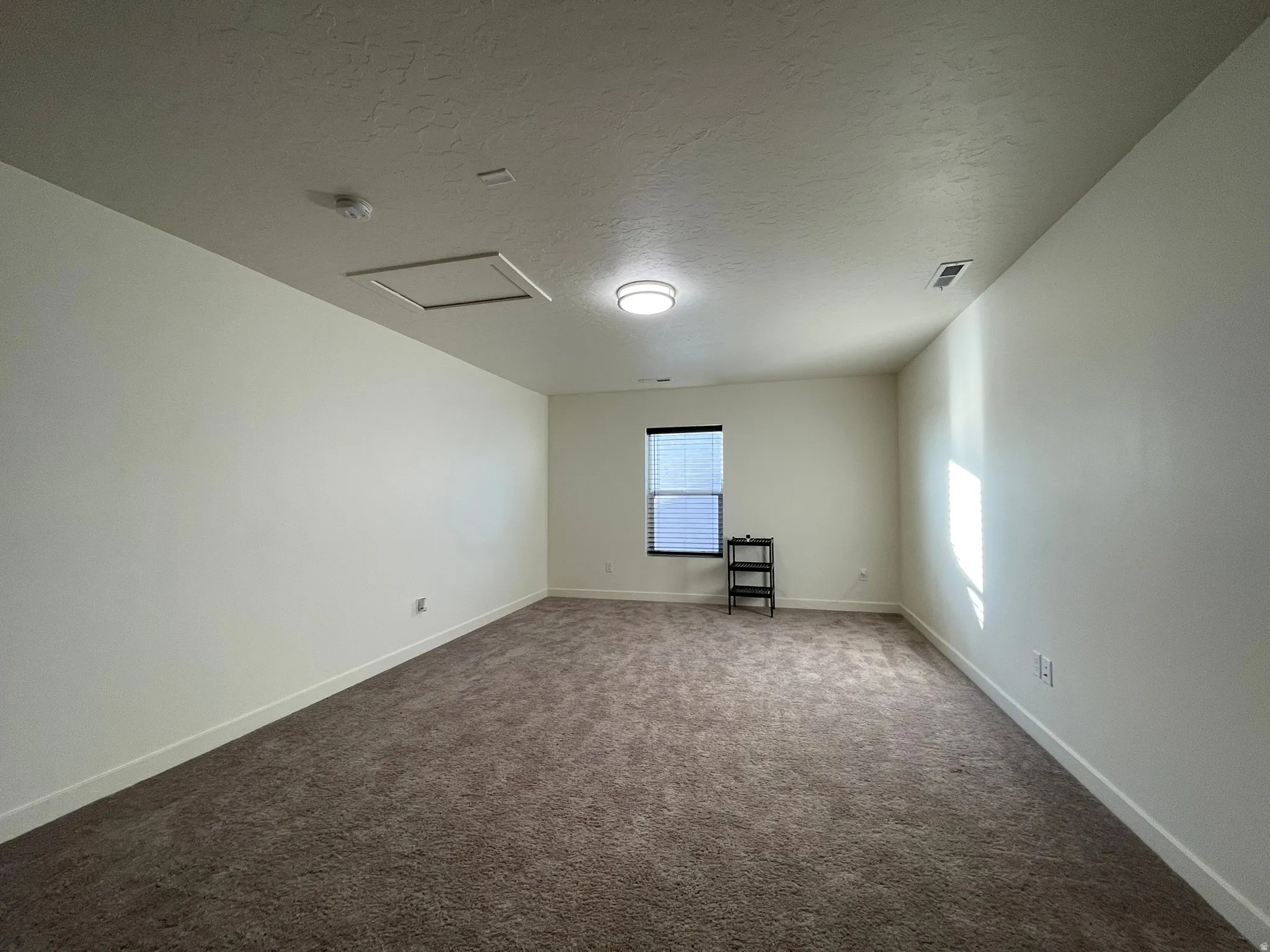 Spare room featuring a textured ceiling and dark carpet