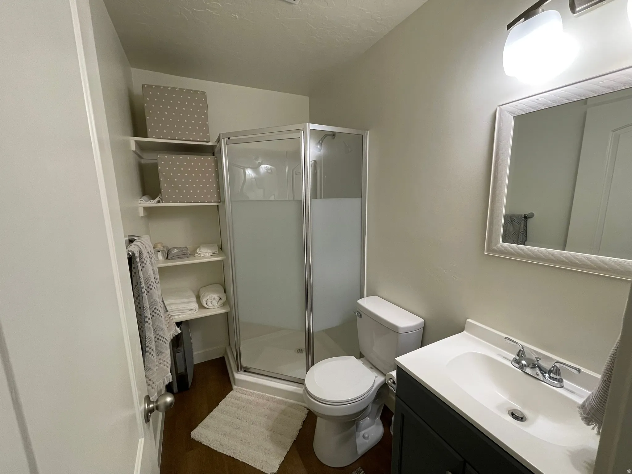 Full bath featuring vanity, a stall shower, and dark wood-type flooring