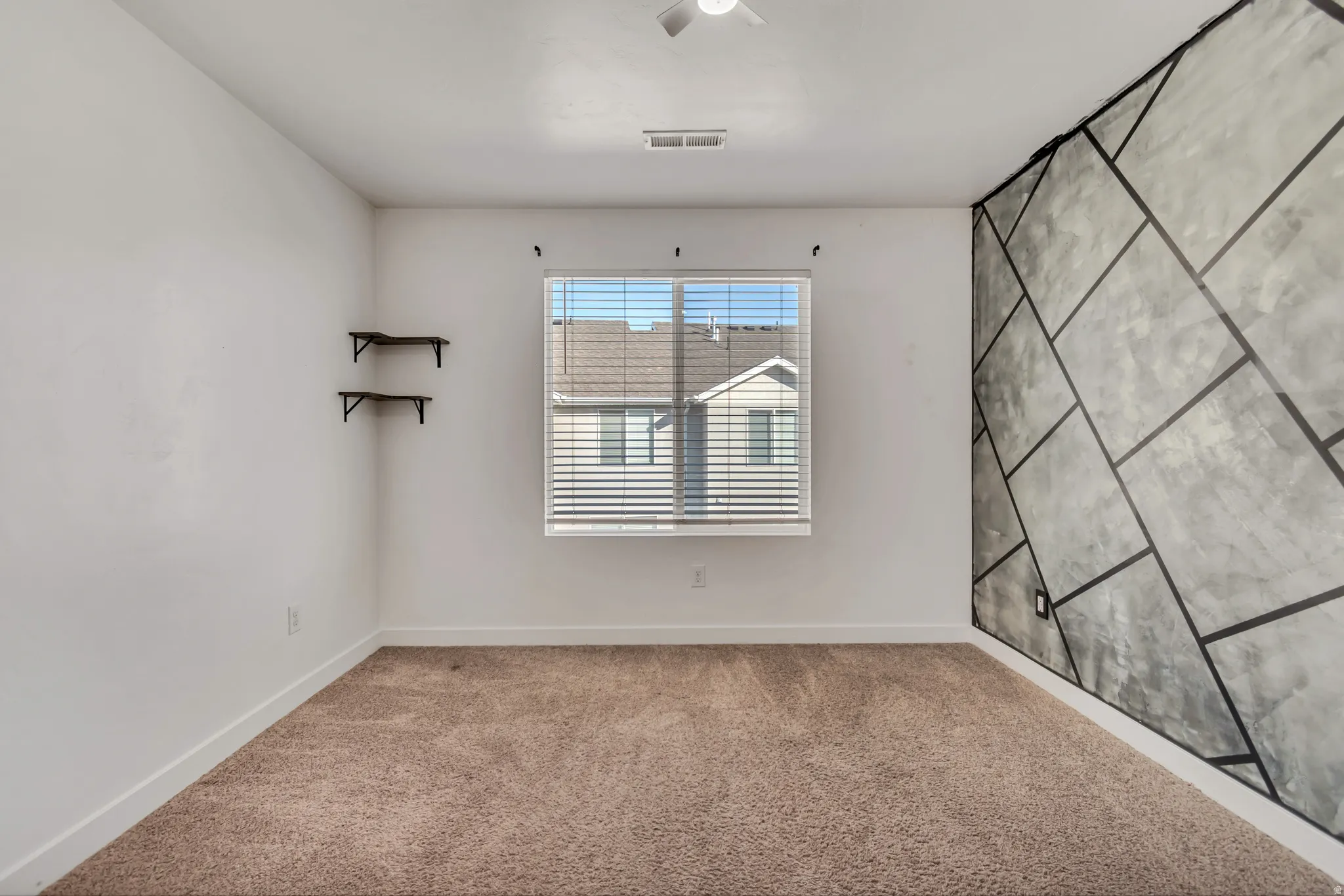 Carpeted empty room with an accent wall and baseboards