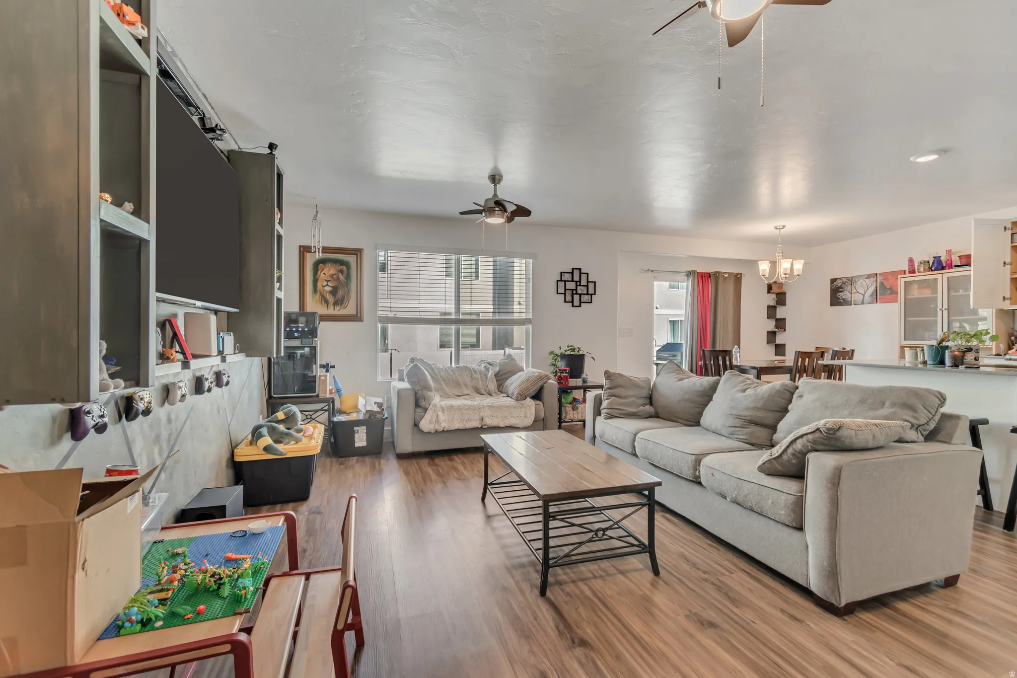 Living room featuring a ceiling fan, wood finished floors, and suspended lighting