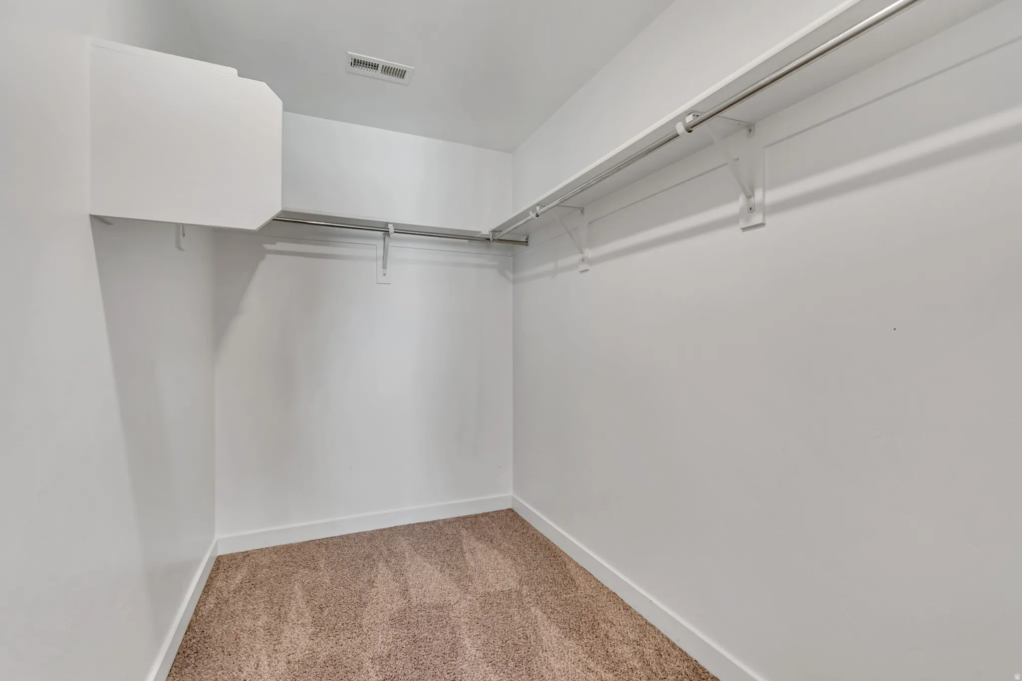 Walk in closet with light carpet