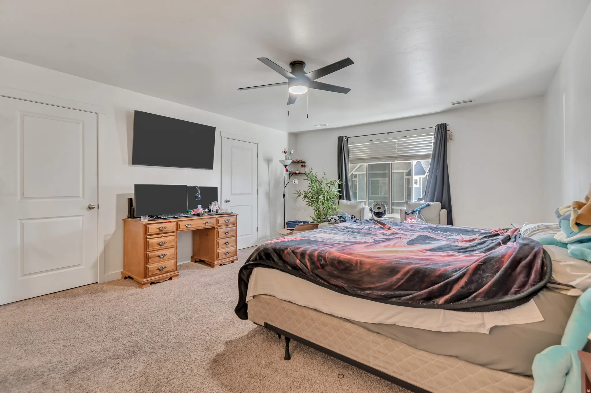 Bedroom with light colored carpet and a ceiling fan