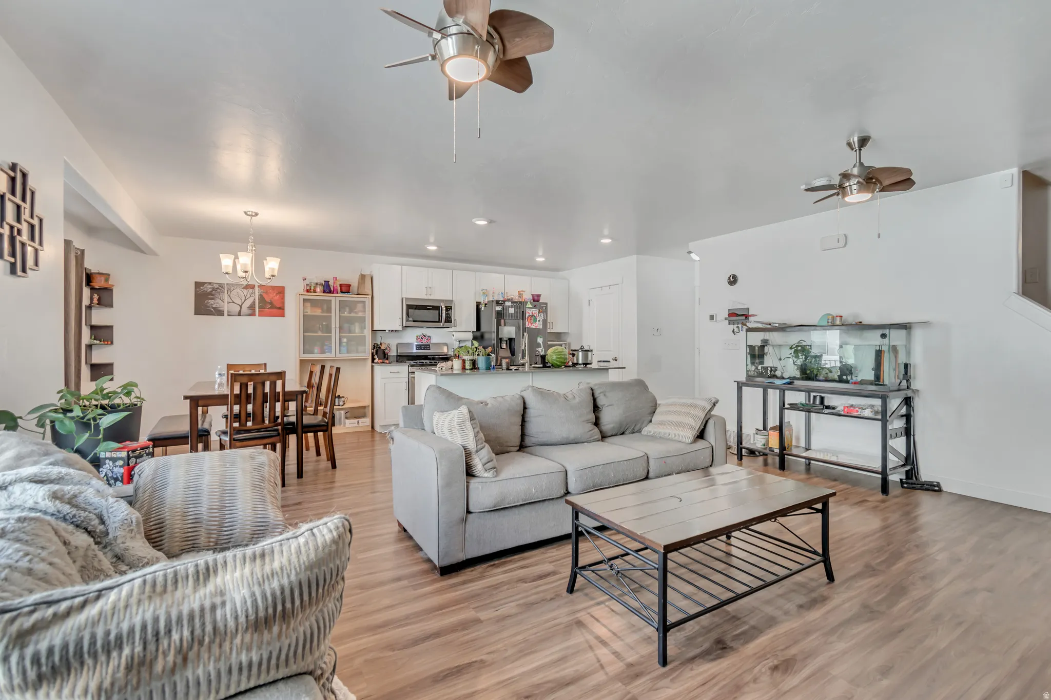 Living room with ceiling fan, light wood-style flooring, and a chandelier