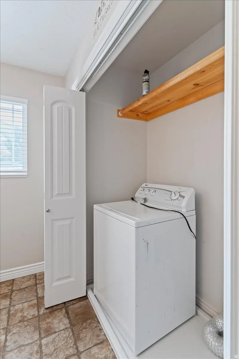 Laundry area featuring washer / dryer and light stone finish floors