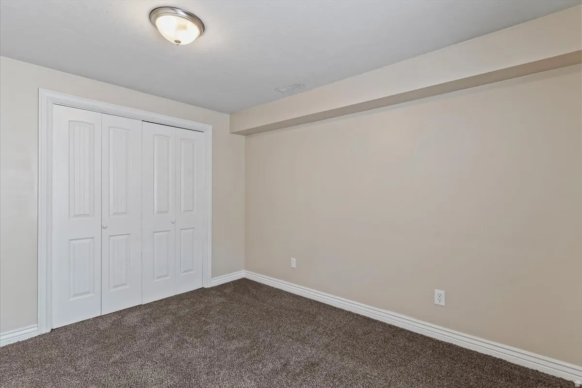 Unfurnished bedroom featuring a closet and dark colored carpet