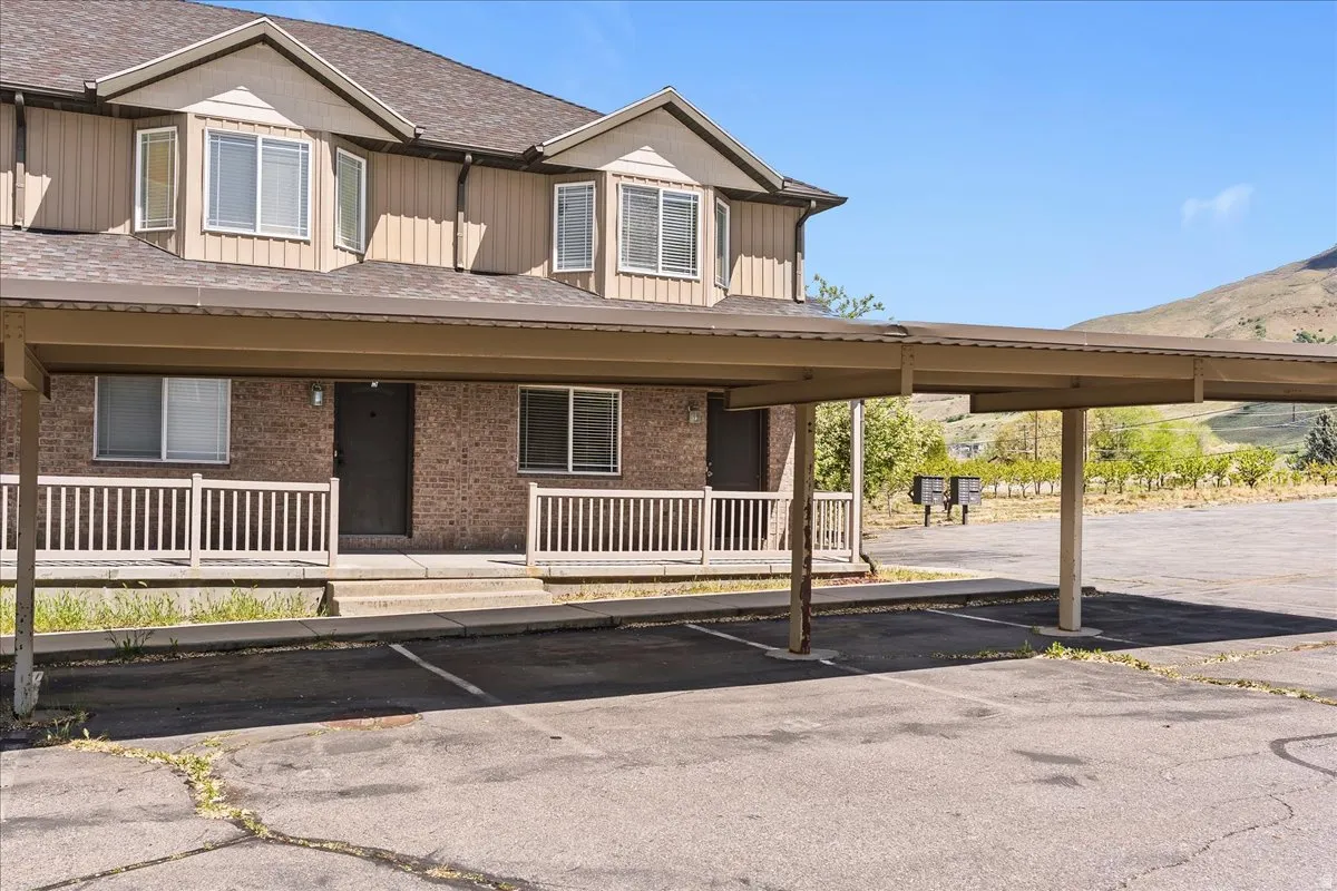View of front of home with board and batten siding, covered porch, and covered parking