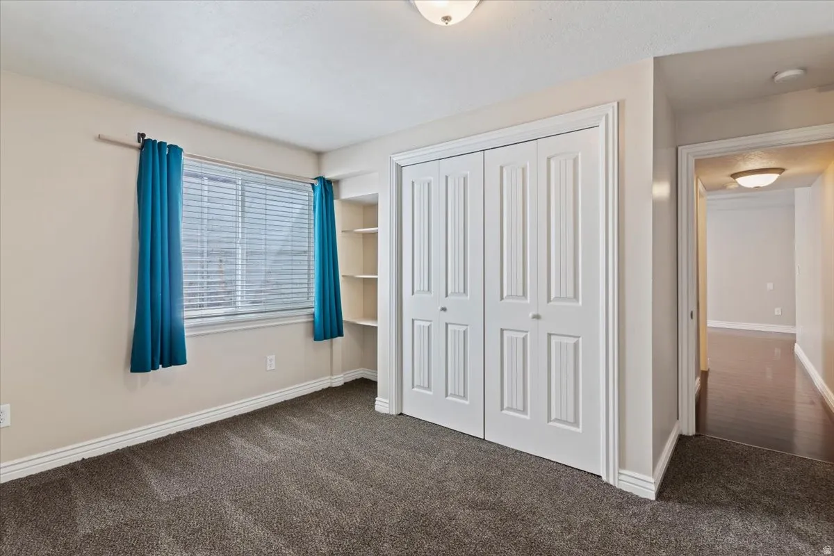 Unfurnished bedroom featuring dark carpet and a closet