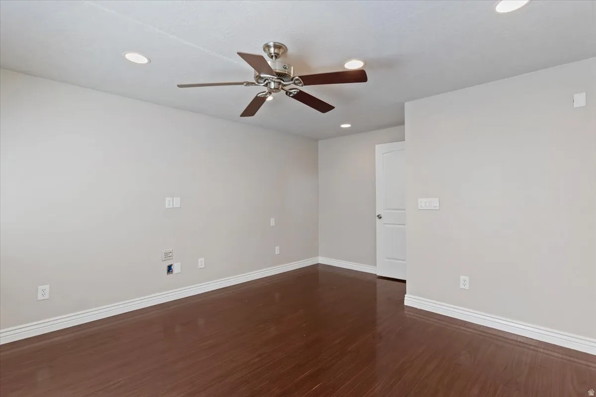 Unfurnished room featuring dark wood-style flooring, ceiling fan, and recessed lighting