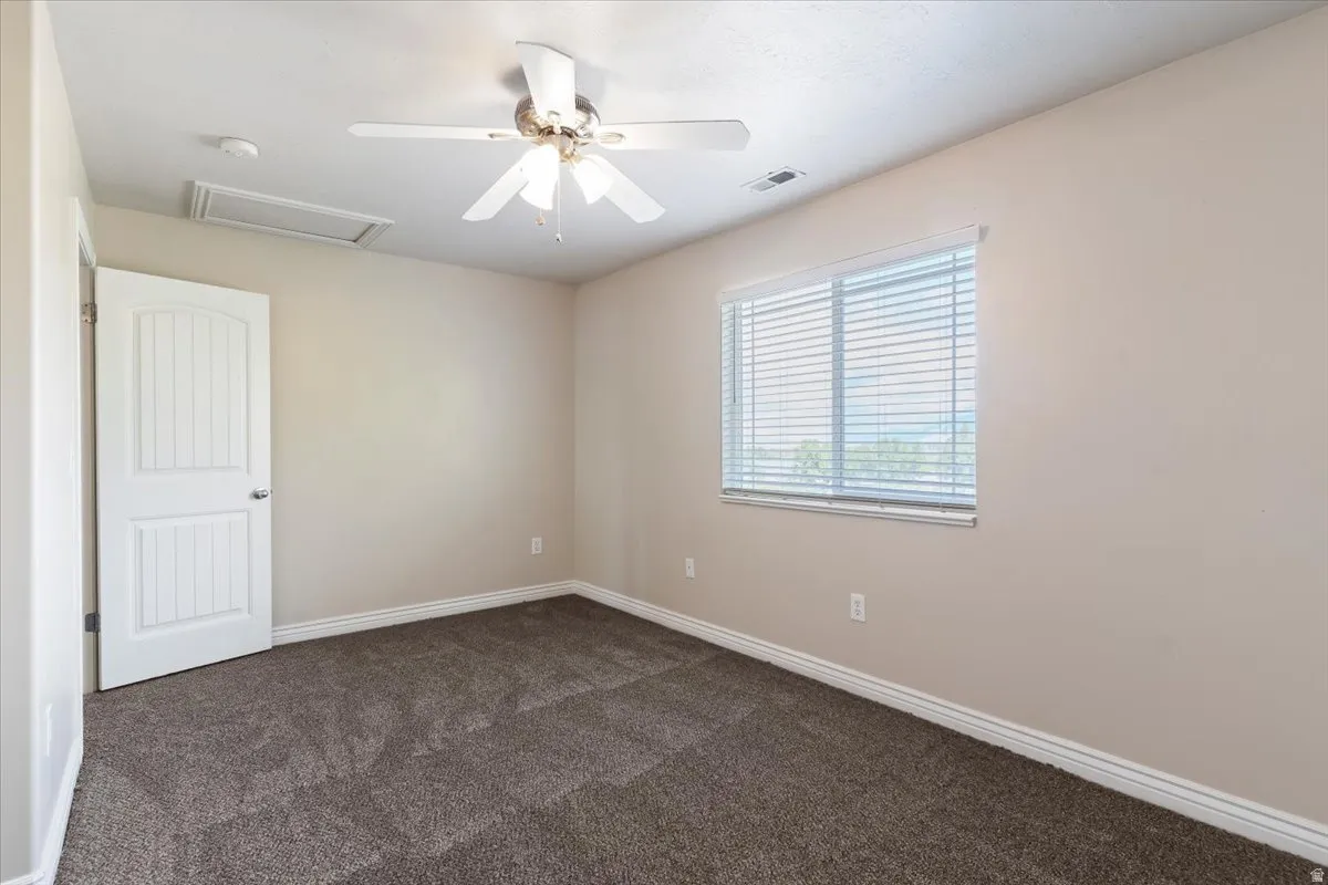 Spare room with a ceiling fan and dark carpet