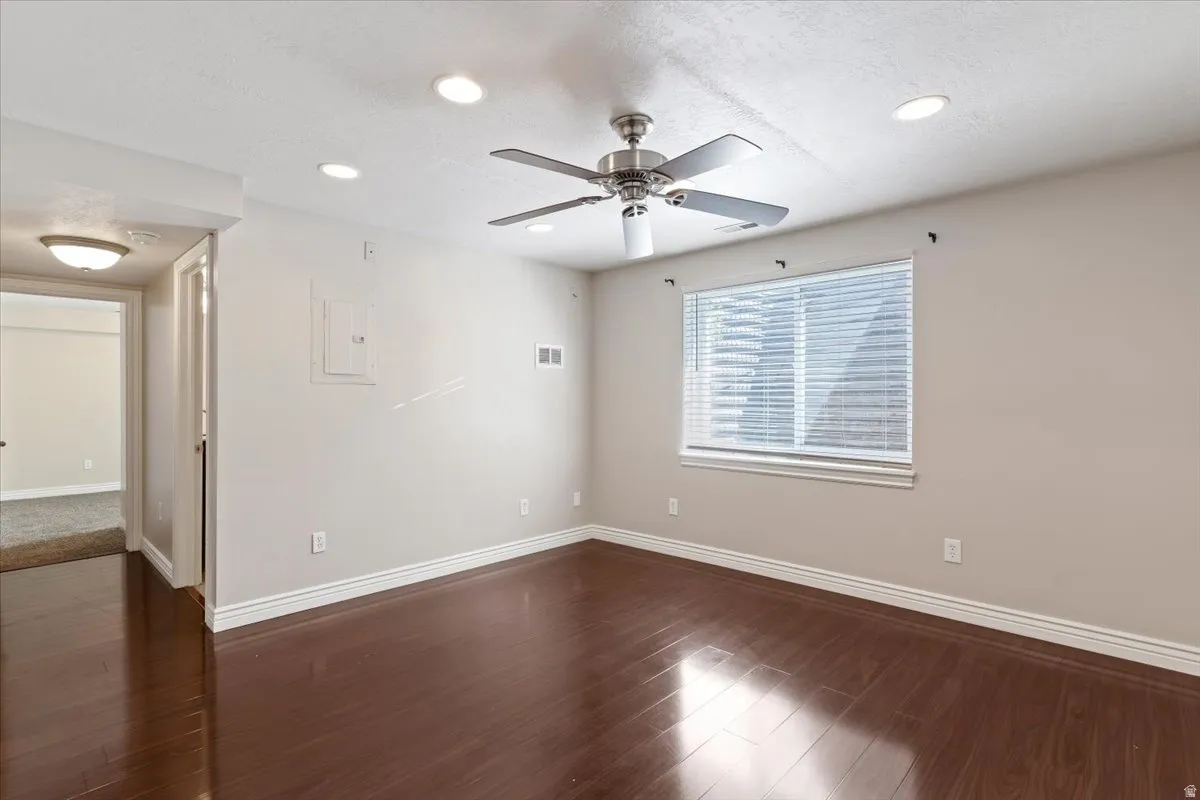Spare room featuring dark wood-style floors, electric panel, ceiling fan, a textured ceiling, and recessed lighting