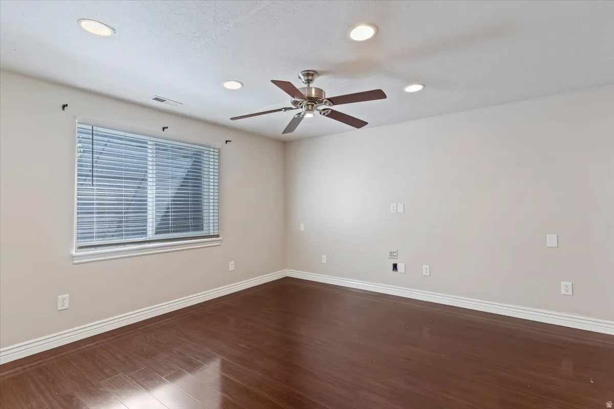 Empty room featuring dark wood-style flooring, a ceiling fan, and recessed lighting