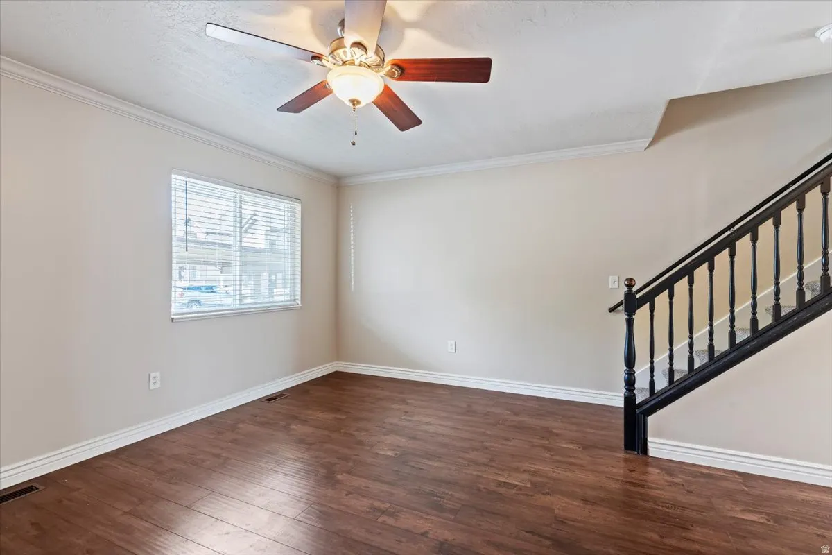 Unfurnished room with ceiling fan, dark wood-style flooring, and crown molding