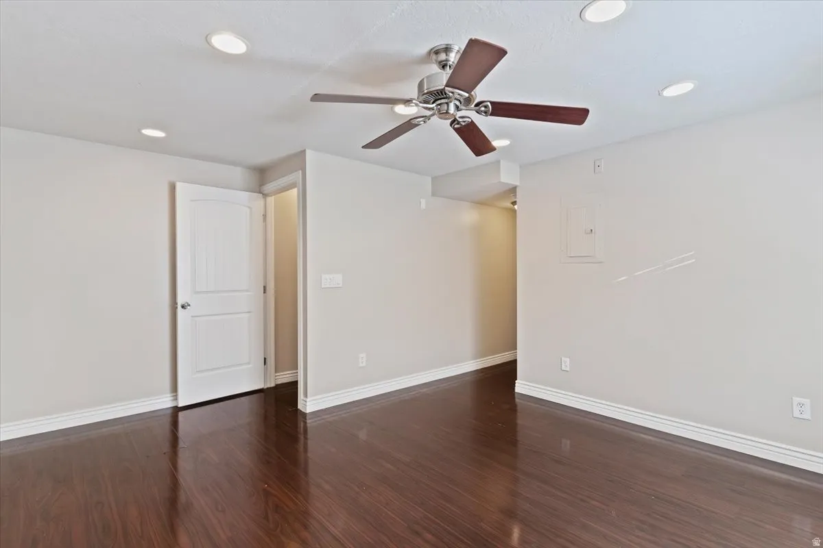 Spare room with ceiling fan, dark wood-type flooring, electric panel, and recessed lighting