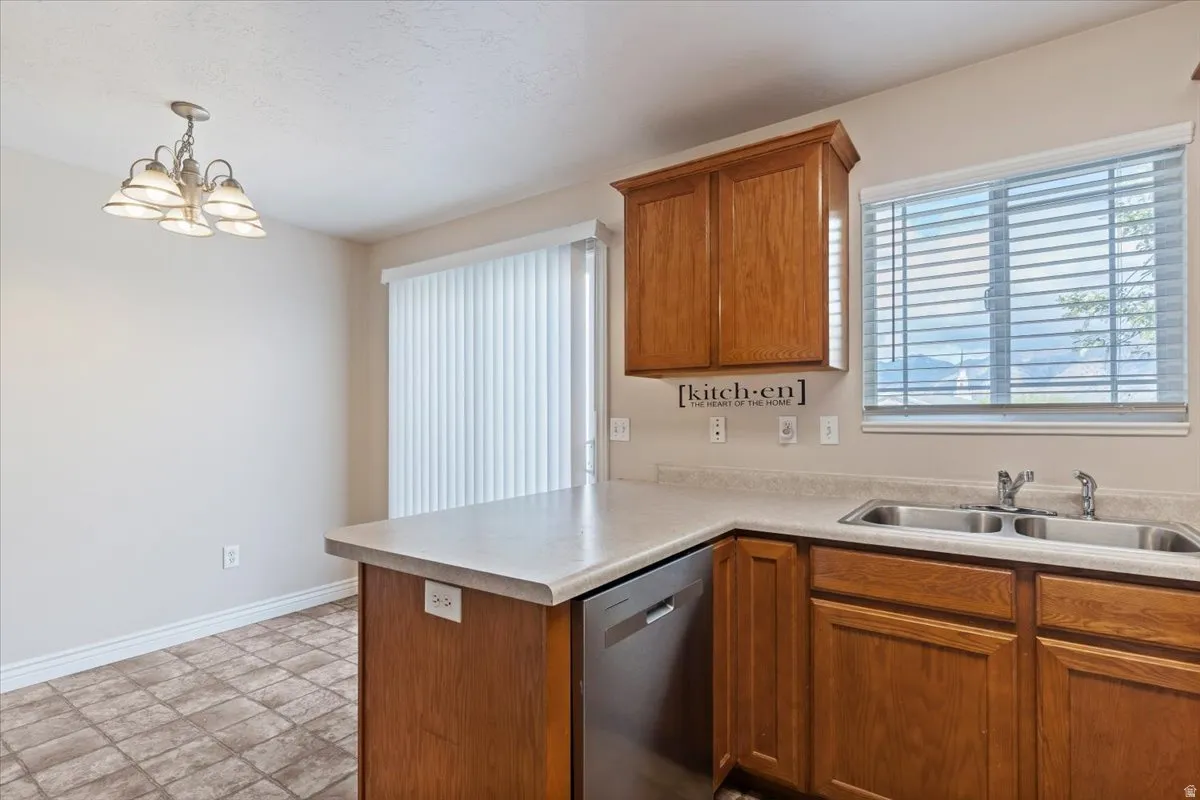 Kitchen with wood finish cabinetry, a peninsula, dishwasher, and light countertops
