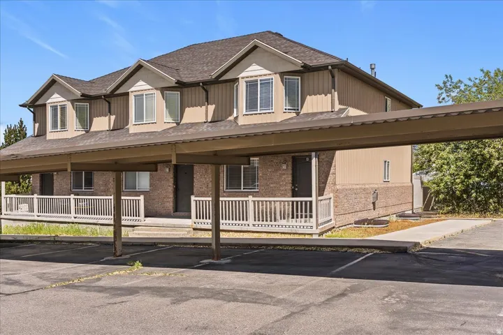View of front of house with board and batten siding, covered parking, and brick siding