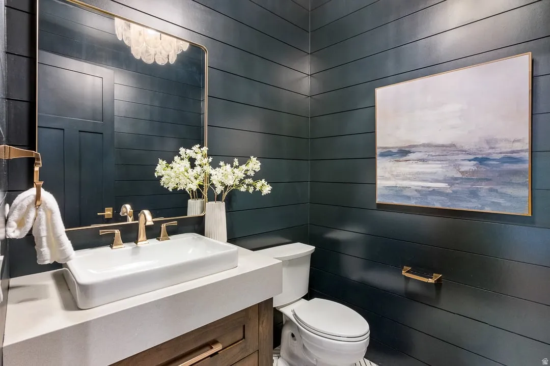 Half bathroom with vanity and wood walls