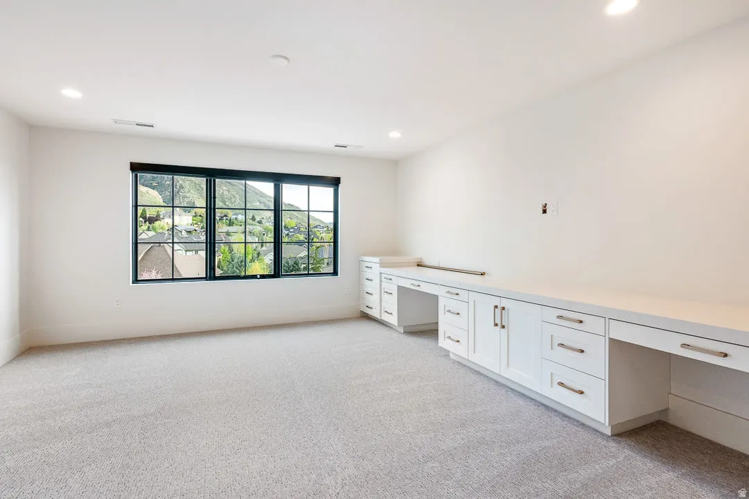 Unfurnished office featuring built in study area, light colored carpet, and recessed lighting