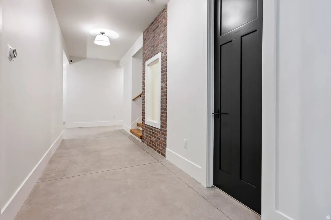 Hall featuring finished concrete flooring and brick wall