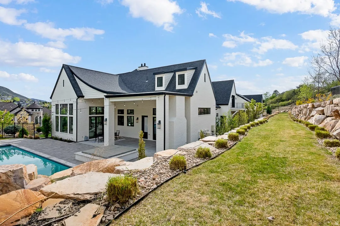 Back of property with a patio, brick siding, a shingled roof, and a chimney