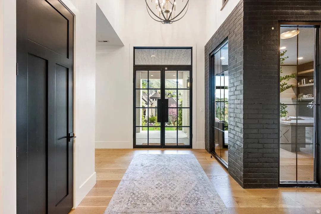 Foyer featuring light wood-style floors, a high ceiling, french doors, and a chandelier