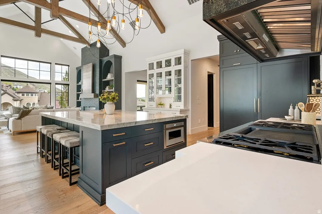 Kitchen featuring light stone countertops, two tone cabinets, light wood-type flooring, a spacious island, and open floor plan