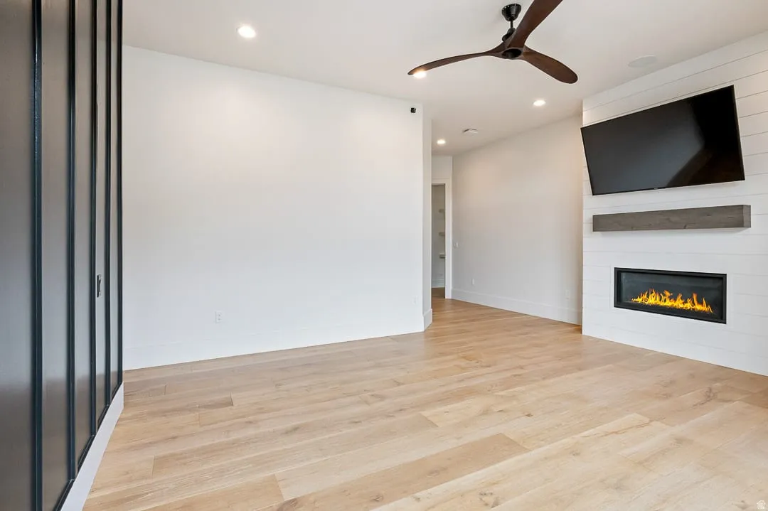 Unfurnished living room with ceiling fan, recessed lighting, light wood finished floors, and a fireplace