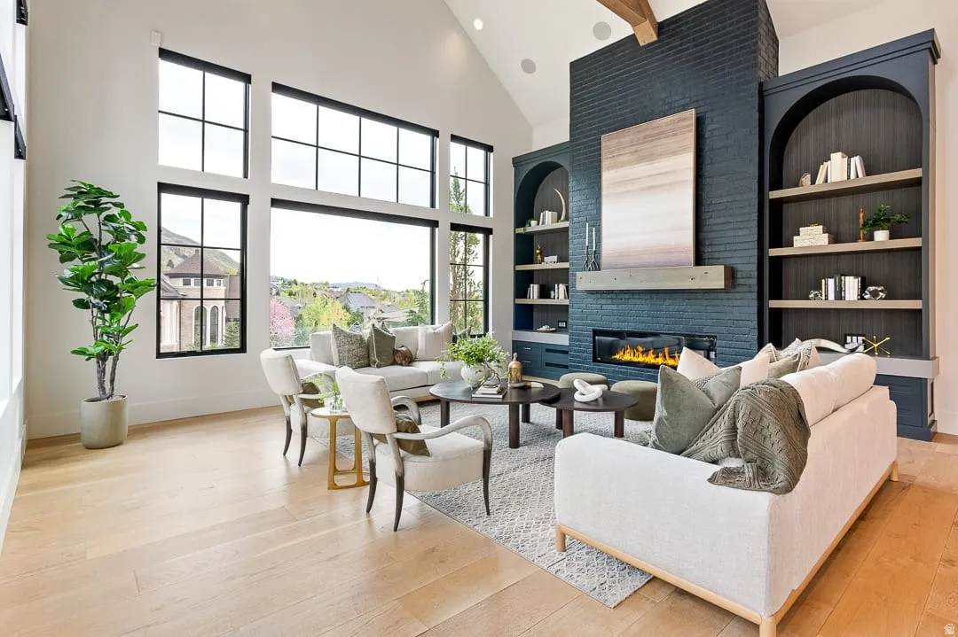 Living area with a large fireplace, light wood finished floors, built in features, recessed lighting, and vaulted ceiling