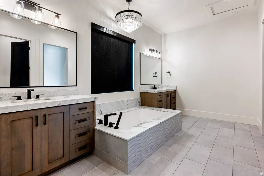 Full bathroom with two vanities, a bath, light tile patterned floors, and suspended lighting