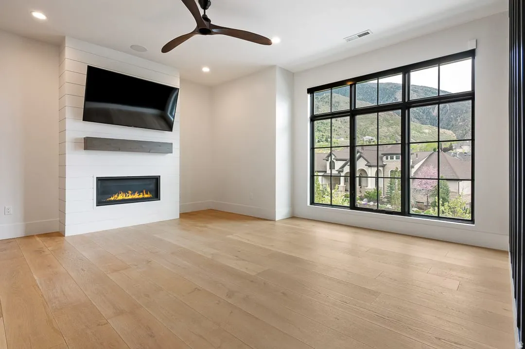 Unfurnished living room featuring ceiling fan, light wood-style flooring, a fireplace, and recessed lighting