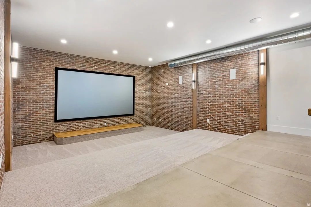 Home theater room with brick wall, recessed lighting, and concrete flooring