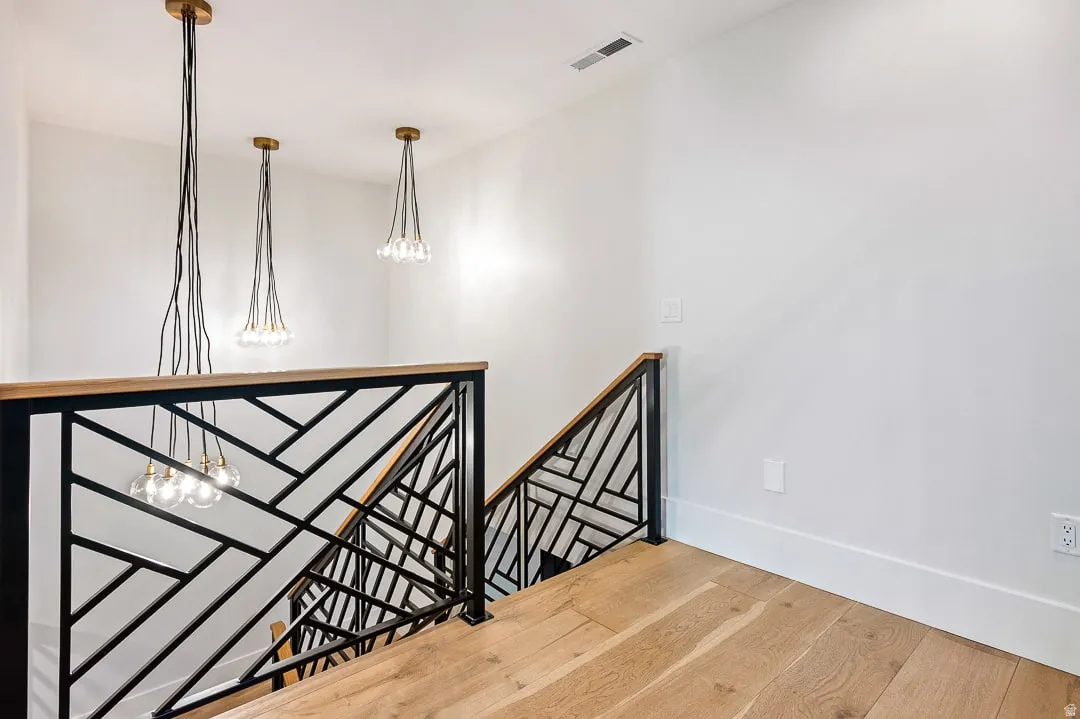 Staircase featuring suspended lighting and wood-type flooring