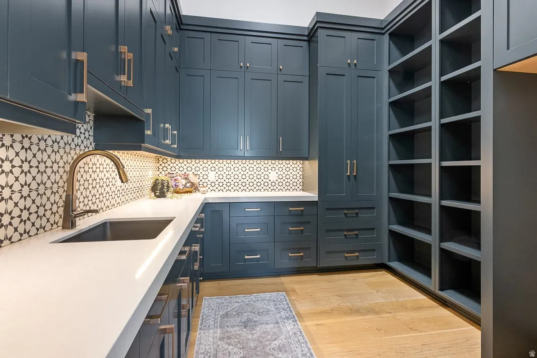 Kitchen with light wood finished floors, decorative backsplash, light stone countertops, and blue cabinets