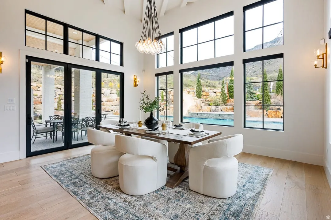 Dining space featuring light wood-type flooring, hanging lights, a high ceiling, and plenty of natural light