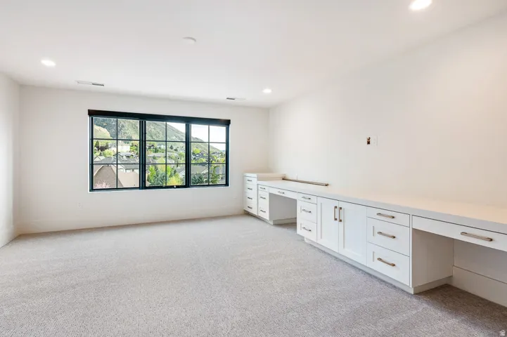 Unfurnished office featuring built in study area, light colored carpet, and recessed lighting