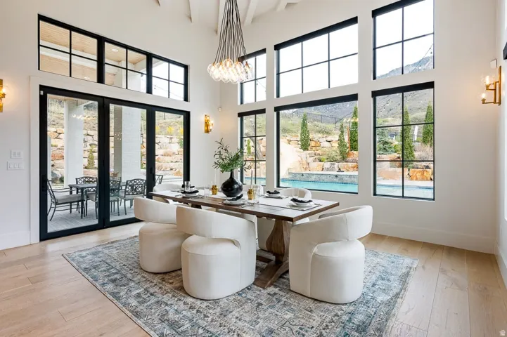 Dining space featuring light wood-type flooring, hanging lights, a high ceiling, and plenty of natural light