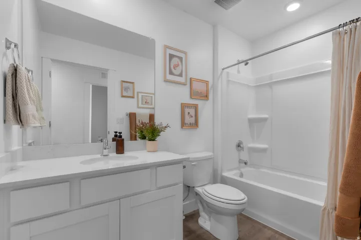 Full bath featuring vanity, dark wood-style floors, and shower / tub combo
