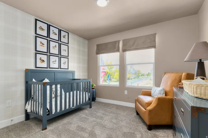 Carpeted bedroom featuring a crib and wallpapered walls