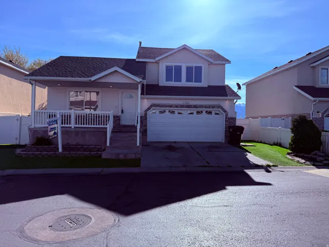 View of front of property featuring covered porch, a shingled roof, concrete driveway, an attached garage, and stucco siding