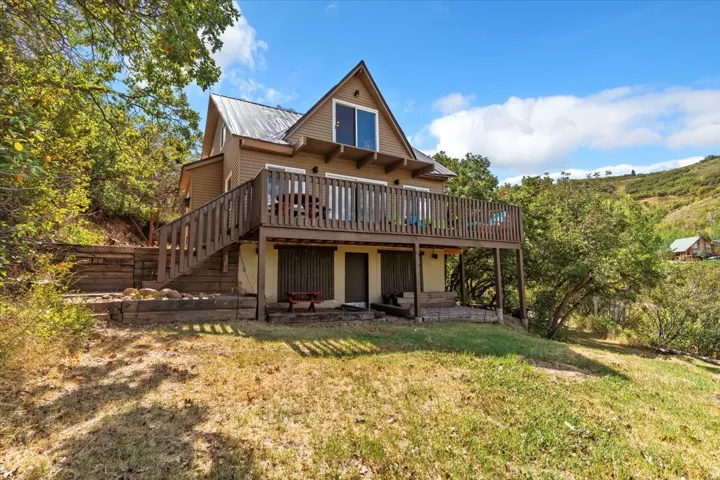 Property featuring a wooden deck, a yard, and a metal roof