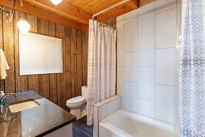 Full bathroom featuring vanity, shower / bath combination with curtain, and dark wood finished floors