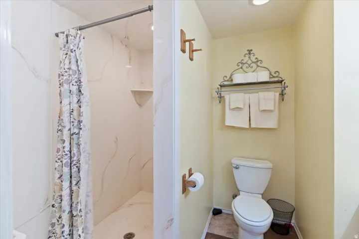 Bathroom featuring toilet and a marble finish shower