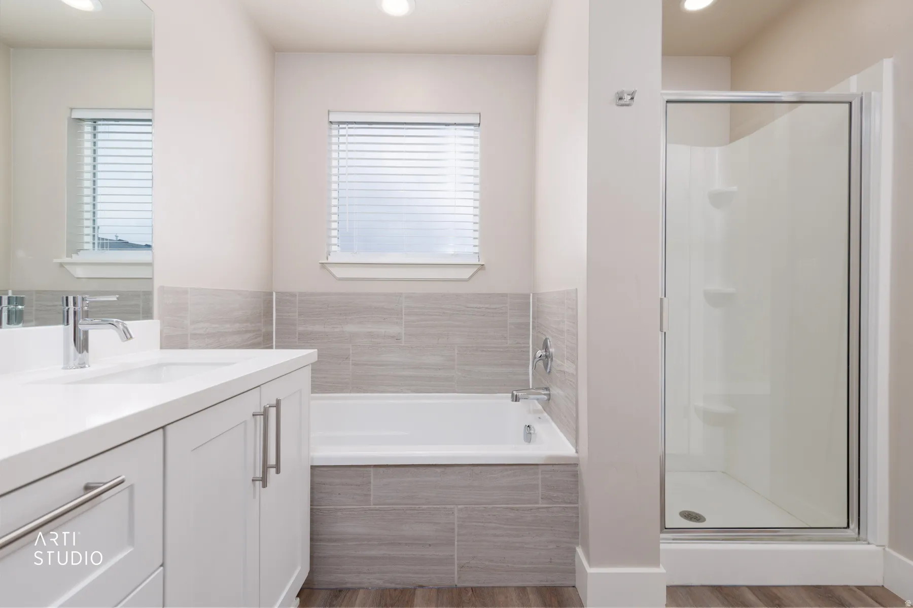 Full bath featuring vanity, light wood-style flooring, a shower stall, a garden tub, and recessed lighting