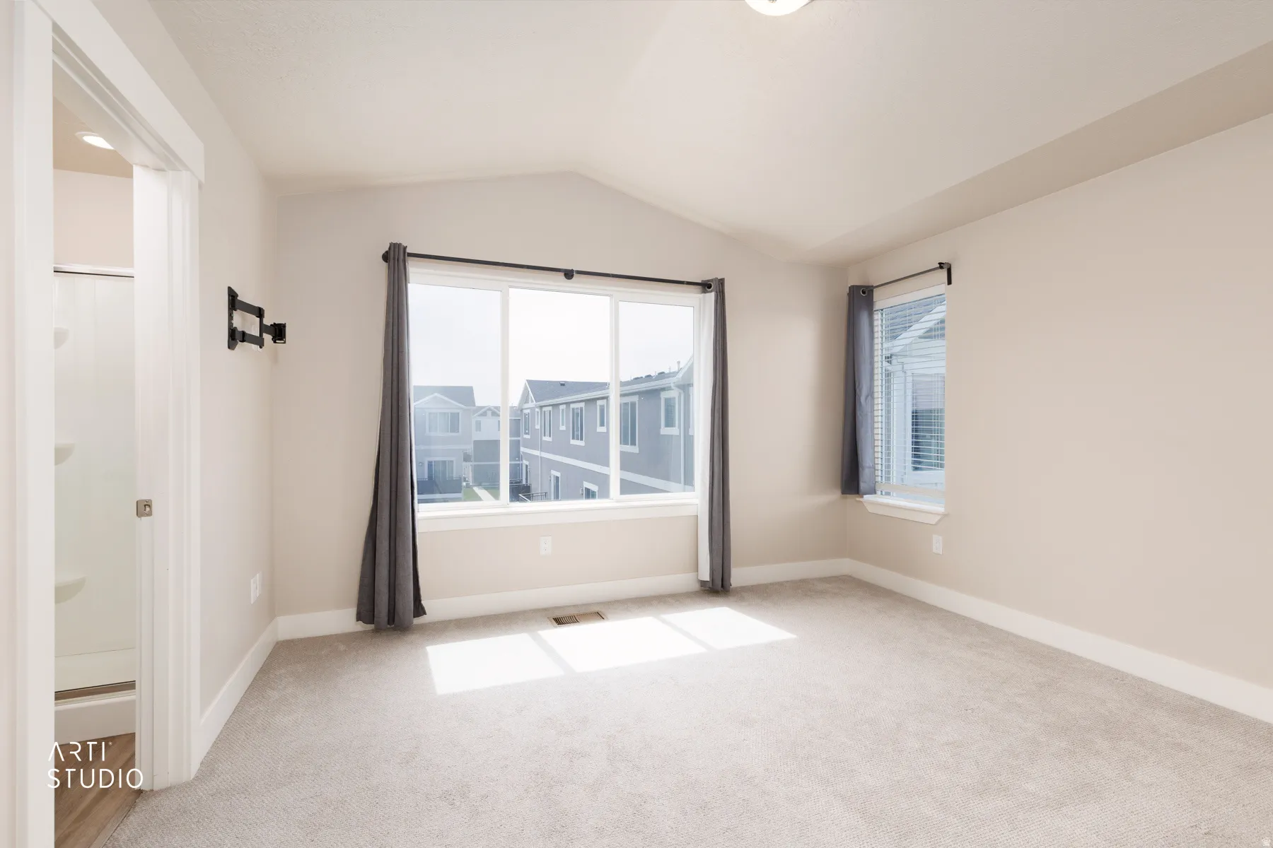 Primary bedroom featuring lofted ceiling and light colored carpet