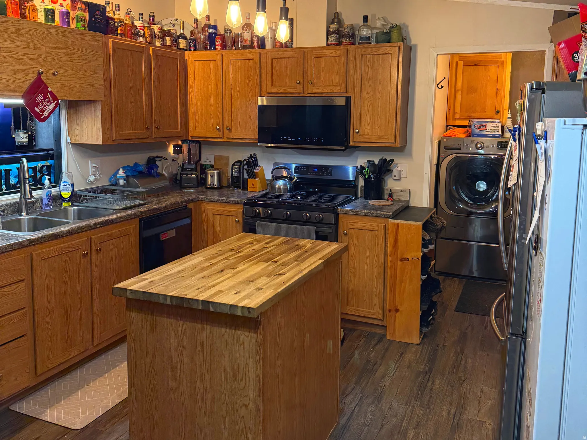 Kitchen featuring wood finish cabinets, stainless steel appliances, dark wood-style flooring, and crown molding