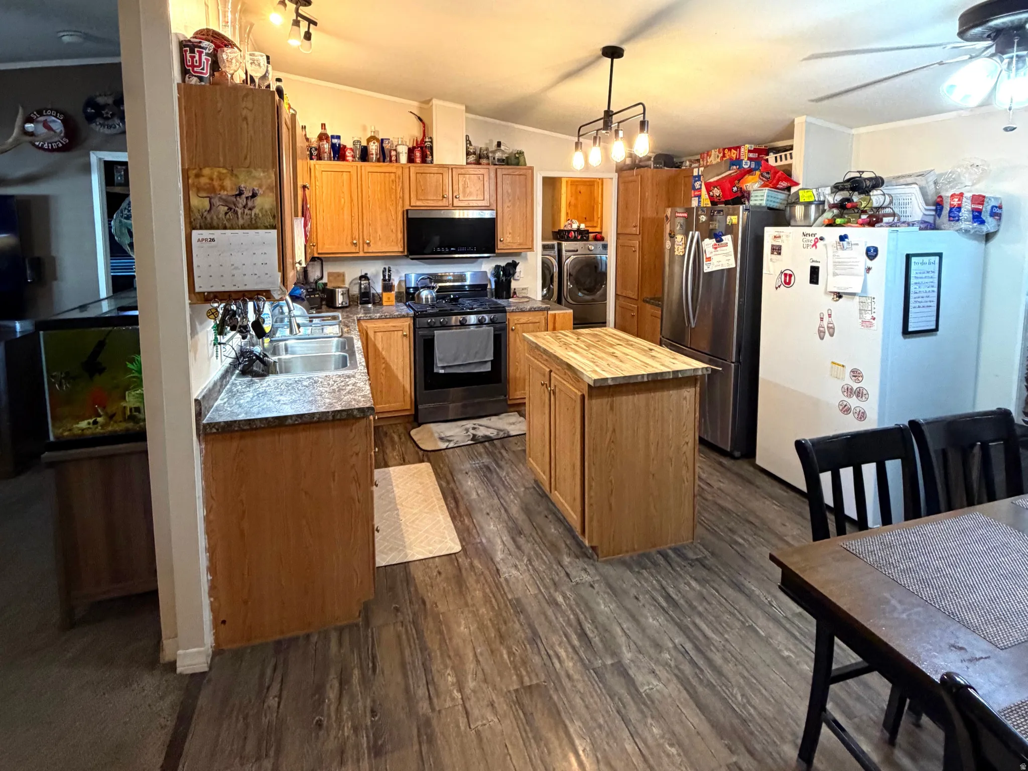 Kitchen featuring stainless steel appliances, a center island, separate washer and dryer, dark wood finished floors, and ceiling fan