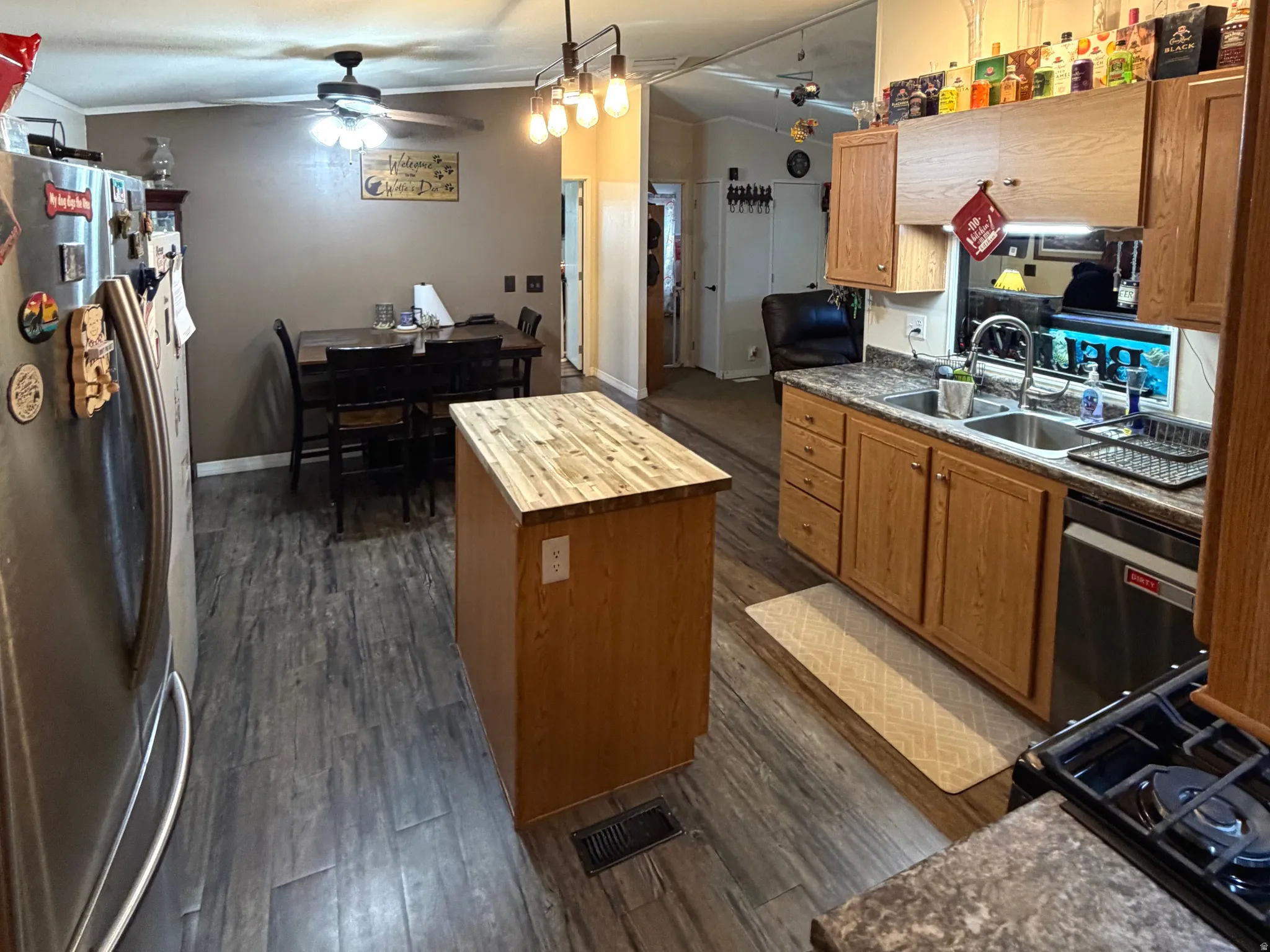 Kitchen featuring stainless steel appliances, lofted ceiling, a kitchen island, wood finish cabinets, and dark wood-type flooring